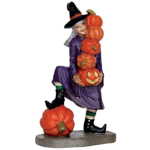Polyresin figurine for a Lemax display. Designed to look like a witch juggling five pumpkins while standing on a larger pumpkin. She's wearing a purple cloak and a black pointy hat.