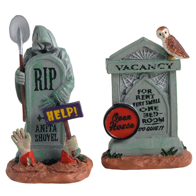 Polyresin village accessories for a Lemax display. Designed to look like two tombstones. One tombstone reads "RIP. ANITA SHOVEL." There are two hands breaking through the dirt, one of the hands is holding a sign that reads "Help!" The grim reaper is part of the tombstone and is holding a shovel. The other tombstone reads "VACANCY. FOR RENT. VERY SMALL ONE BEDROOM. SO QUIET! OPEN HOUSE." There's an owl sitting on top.
