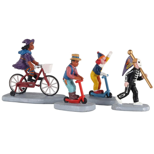 Polyresin figurines for a Lemax display. Designed to look like four kids getting ready to trick or treat. One girl is dressed as a witch and is riding a red tricycle. One kid is dressed in a brown top hat, a blue vest, a pink shirt and is wearing light blue pants with brown boots and he's riding a red scooter. One kid is dressed like a clown and is riding a blue scooter. The other kid is leading the others with a Halloween flag and is dressed like a skeleton.