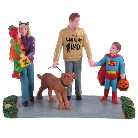 Polyresin village accent for a Lemax Spooky Town display. Designed to look like two parents trick or treating with their kids and their dog. They're walking on a sidewalk with grass on both sides. The dad is wearing a tan sweater that reads "The Walking Dad." The mom is wearing cat ears and is holding a child dressed like a pumpkin. The other child is holding hands with the dad and is dressed like Superman.