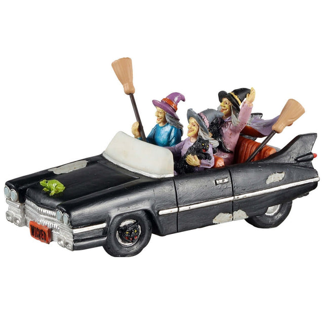 Polyresin figurine for a Lemax display. Designed to look like three witches out for a drive. They're all holding broomsticks, and two of them are holding black cats. There's a green toad on the front of the car.