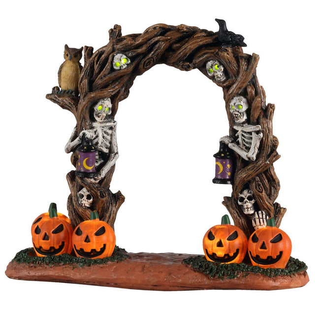Plastic village accessory for a Lemax Spooky Town display. Designed to look like an arch made of branches. There are skulls and crows and an owl perched on it. There are two skeletons inside the arch that are holding lights. There are four jack-o-lanterns at the base.