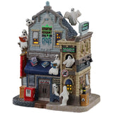 Porcelain lighted building for a Lemax Spooky Town display. Designed to look like a school with different ghosts throughout. Some of the ghosts are reading on the roof. There's a newspaper box on the sidewalk.
