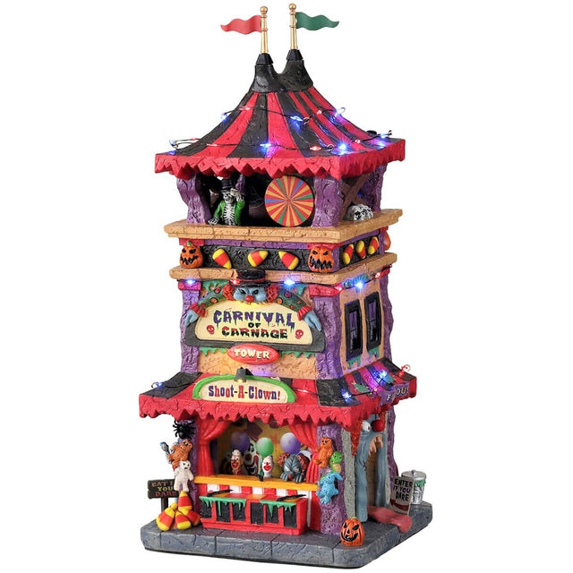 Polyresin lighted building for a Lemax display. Designed to look like a tall, carnival tower with a red and black striped tarp on top. There are jack-o-lantern, skull and candy corn accents. The bottom of the tower has a sign that reads "SHOOT A CLOWN!" and has a little booth with prizes and balloons.