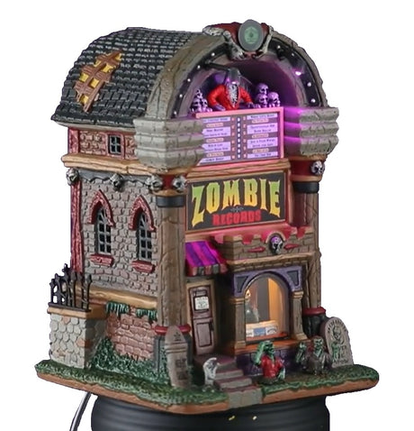Porcelain lighted building for a Lemax display. Designed to look like a building shaped like a jukebox. There are skeletons and monsters and tombstones. Inside the window you can see a skeleton holding a vinyl record.