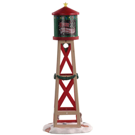 Polyresin figurine for a Lemax Village tabletop display. Designed to look like a red, green and brown water tower. The water tower features Santa's face, a yellow star on the top, a wreath and garland. There are two bunnies in the snow at the bottom