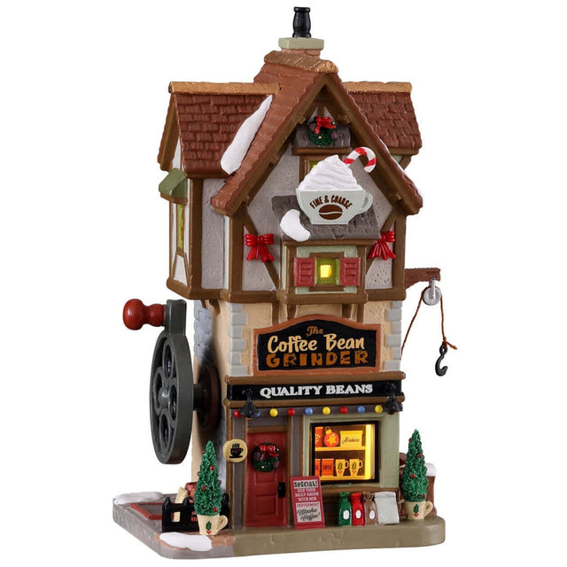 Porcelain lighted building for a Lemax display. Designed to look like a tall cottage. The sign reads "The Coffee Bean Grinder. Quality beans." You can see shelves of cups in the front window. There's snow on the building and features a few small trees in pots shaped like mugs. There's a crank on the side of the building for decoration.