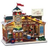 Polyresin lighted building for Lemax display. Designed to look like a wooden post office. There's a red flag on top of the roof that reads "Santa Post." There's a big sign that's shaped like an envelope that reads "Letters to Santa." There's a big clock and it reads "Always on time" underneath. Next to the clock it reads "North Pole Mail Room." There's an elf pushing a big cart of mail.
