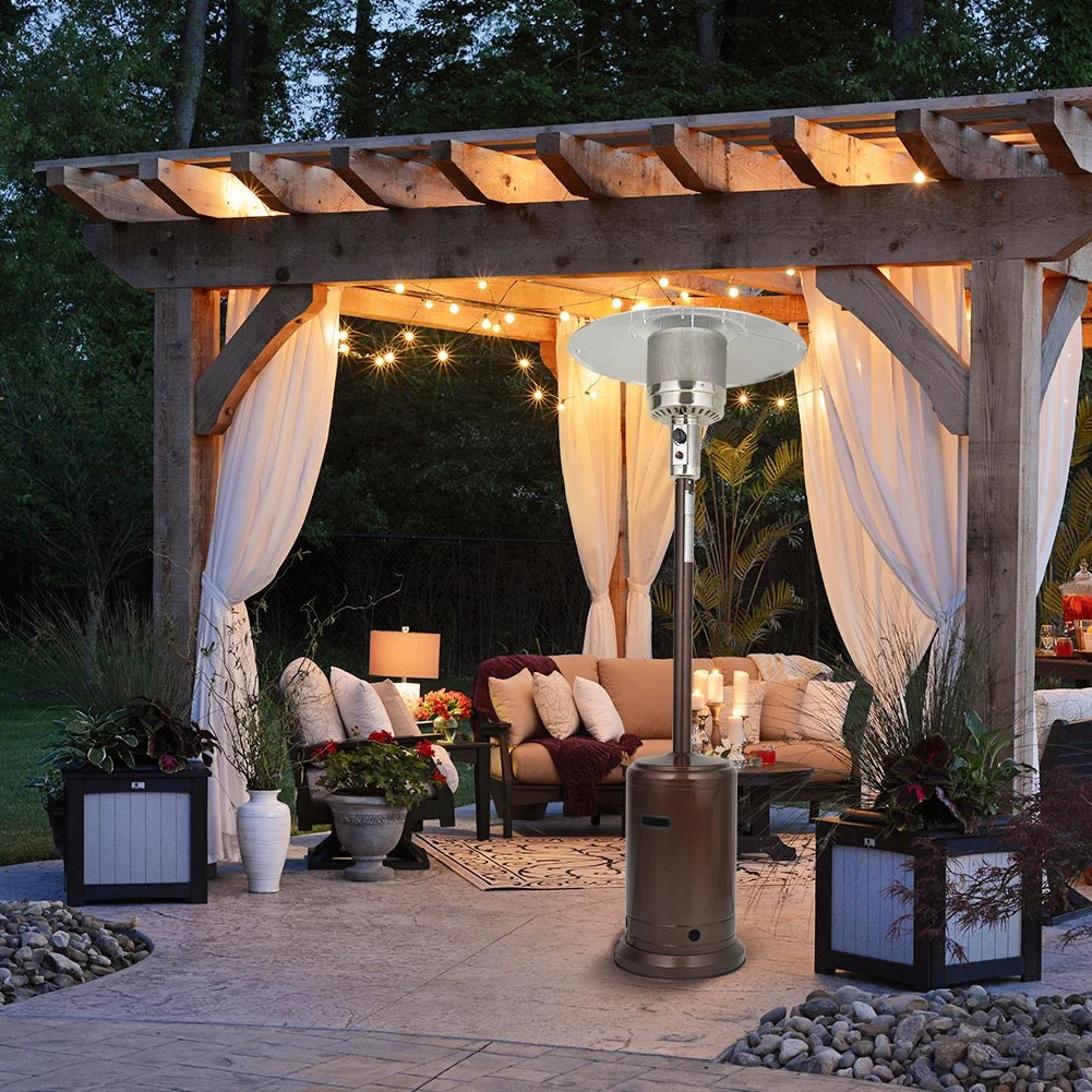 A pergola canopy on a stone patio with a cushioned outdoor patio set and a standing patio heater underneath it