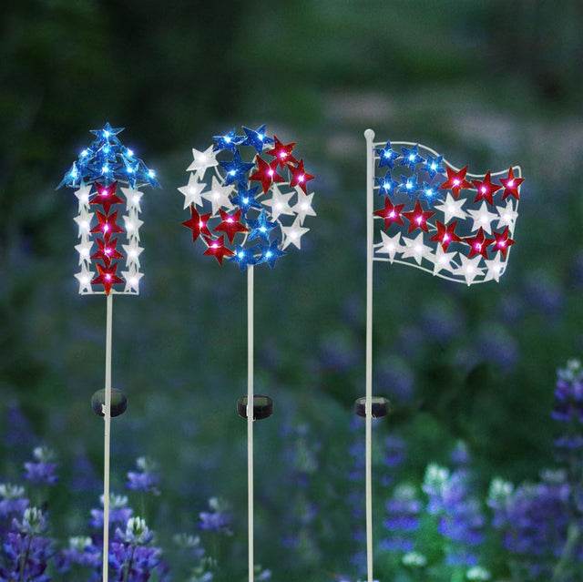Solar powered patriotic garden stake. One is shaped like an arrow pointing up. One is a circle. The other is shaped like a flag. Each of them is made up of red, white and blue stars.