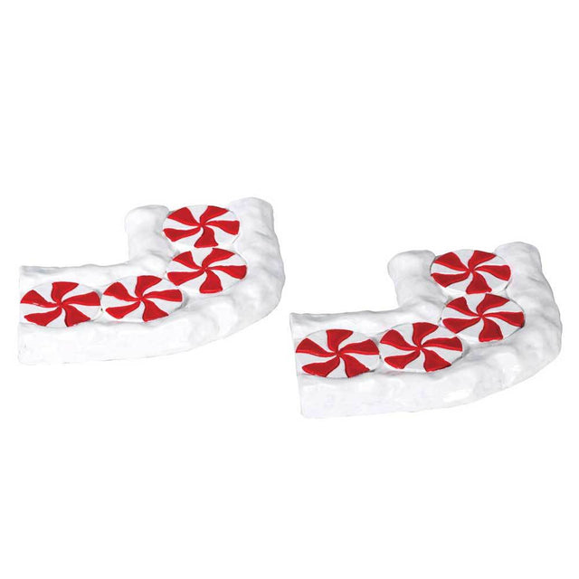 Lemax village accessories designed to look like two curved pieces of a sidewalk. The sidewalk is designed to look like it's covered in snow (or frosting) and red and white peppermint swirls.