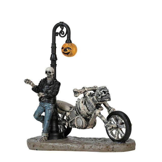 Polyresin figurine for a Lemax display. Designed to look like a skeleton wearing a leather jacket and jeans leaning up against a lamppost. There's a motorcycle made out of bones and skulls next to him. The lamppost light is shaped like a pumpkin.