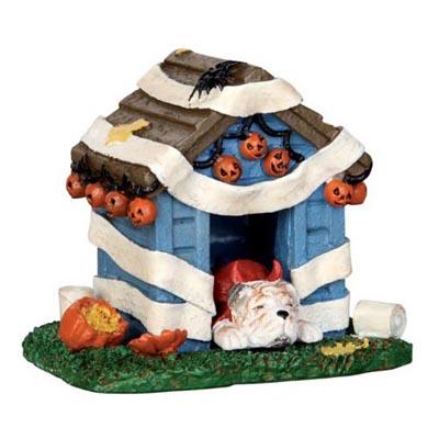 Polyresin figure for a Lemax display. Designed to look like a blue dog house that's been covered in toilet paper. There's a smashed pumpkin on the side and a spider on the roof. There are pumpkin lights hanging off the roof. There's a dog sleeping inside wearing a red devil costume.