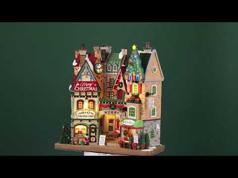 Polyresin building facade for a Lemax display. Designed to look like a collection of store fronts that are decorated for Christmas. Santa is in the front window of one of the stores. There's a person sitting outside of the Wine Bar.