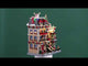 Resin lighted building for a Lemax display. Designed to look like a large, brick apartment complex that's decorated for Christmas. There are elves hanging out of the windows and standing on balconies. There are snowmen, reindeer and a decorated Christmas tree on the roof. Santa is waving from the stairs and there's a dog wearing a Santa hat on the sidewalk.